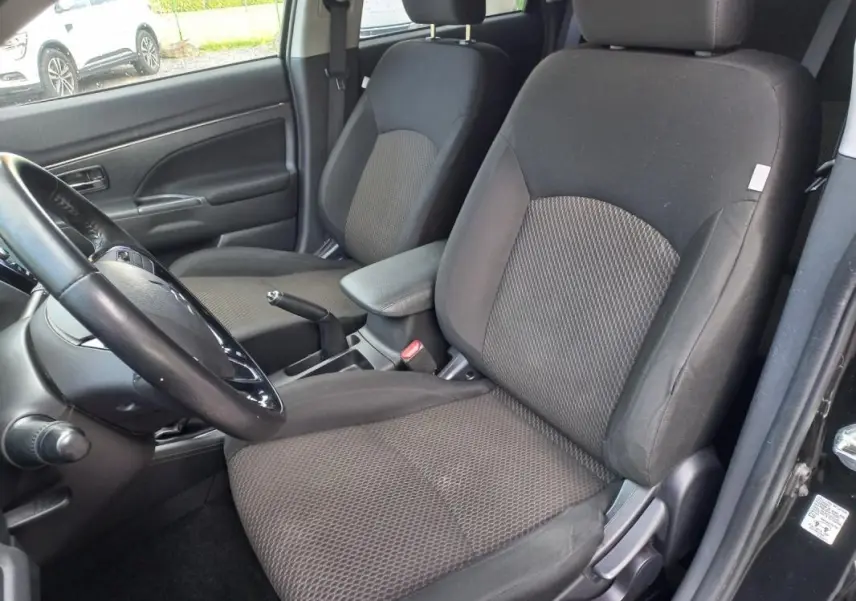 Vue intérieure côté conducteur du Mitsubishi ASX noir 2020, montrant les sièges tissu et l'accoudoir central.