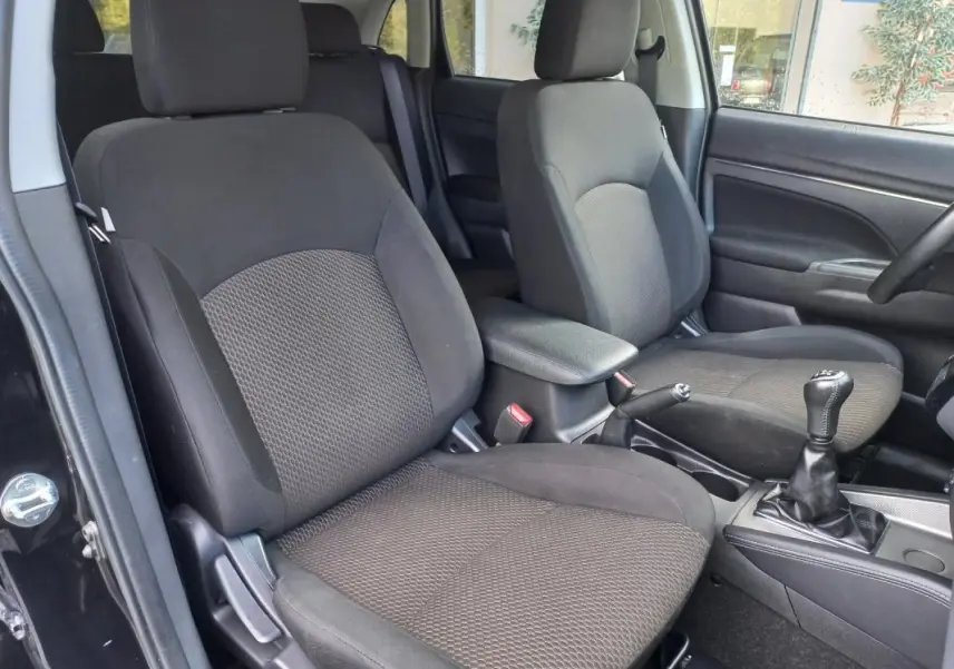 Vue intérieure côté gauche du Mitsubishi ASX noir 2020, montrant les sièges avant et l'accoudoir central.