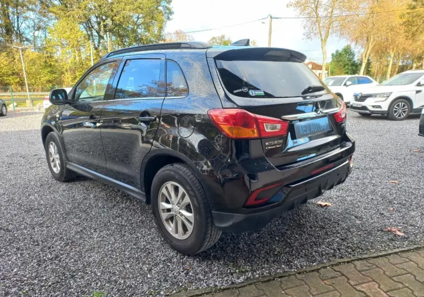 Vue 3/4 arrière droite d’un Mitsubishi ASX noir 2020 garé sur un sol gravillonné, avec jantes 16 pouces visibles.