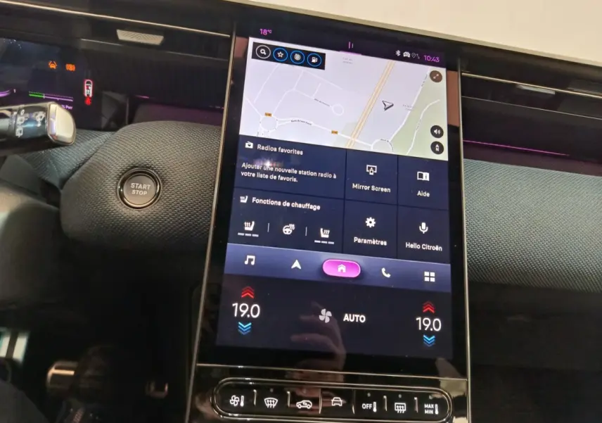 Vue rapprochée du tableau de bord central tactile de la Citroën C5 Hybride gris foncé avec affichage de navigation et commandes climatisation.