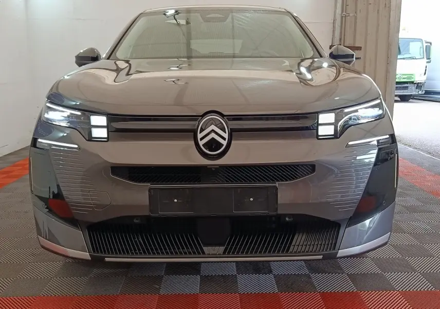Vue frontale d'une Citroën C5 Hybride gris foncé avec phares LED et calandre distinctive en intérieur.