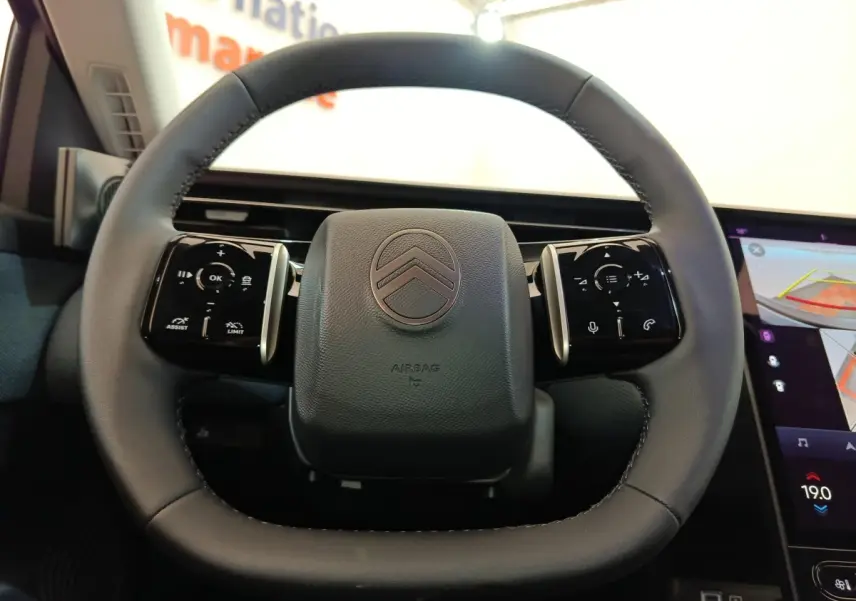 Volant cuir noir de Citroën C5 Hybride 2026, vue frontale avec commandes multifonctions et écran tactile partiel à droite.