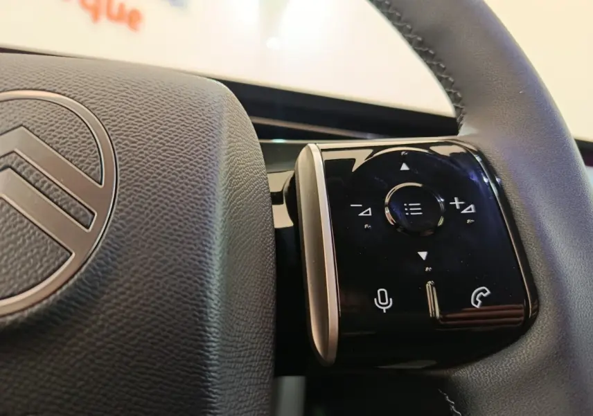 Gros plan sur les commandes tactiles noires du volant cuir de la Citroën C5 hybride gris foncé, intérieur moderne.