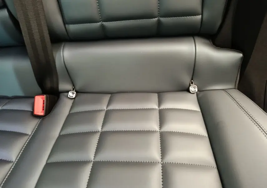 Gros plan sur la banquette arrière en cuir gris foncé de la Citroën C5 Hybride 2026 avec ceintures et ancrages Isofix visibles.