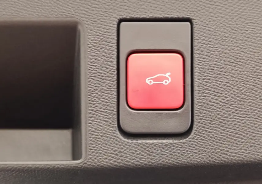 Bouton rouge d'ouverture électrique du coffre sur tableau de bord intérieur d'une Citroën C5 Hybride gris foncé.