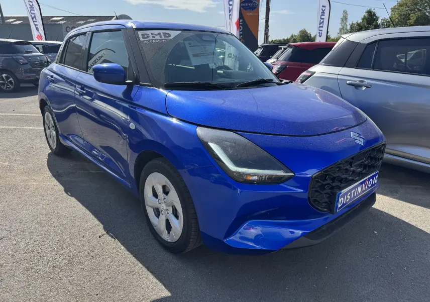 Vue 3/4 avant droit d'une Suzuki Swift 1.2 Privilège Hybrid bleue, avec calandre noire et jantes argentées.