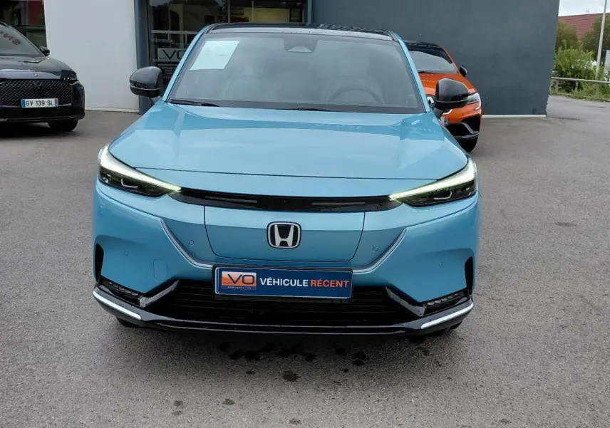 Vue de face du Honda e:Ny1 204 ch Advance bleu électrique 2025 avec phares LED fins et calandre épurée.
