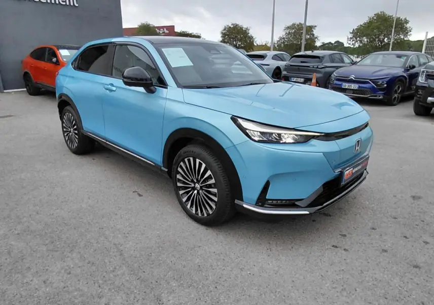 Honda e:Ny1 204 ch Advance bleu en vue 3/4 avant droit, avec jantes distinctives et calandre épurée électrique 2025.