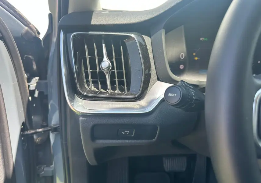 Détail de l'aération et bouton d'ouverture du coffre côté gauche du tableau de bord d'une Volvo S60 Thunder Grey 2024