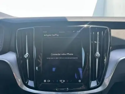 Écran tactile central allumé avec interface Apple CarPlay, entouré de grilles d'aération noires dans l'habitacle d'une Volvo S60 Thunder Grey.