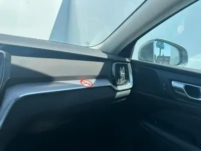 Intérieur côté passager du Volvo S60 2024, tableau de bord noir avec insert argent et sortie d'air carrée.