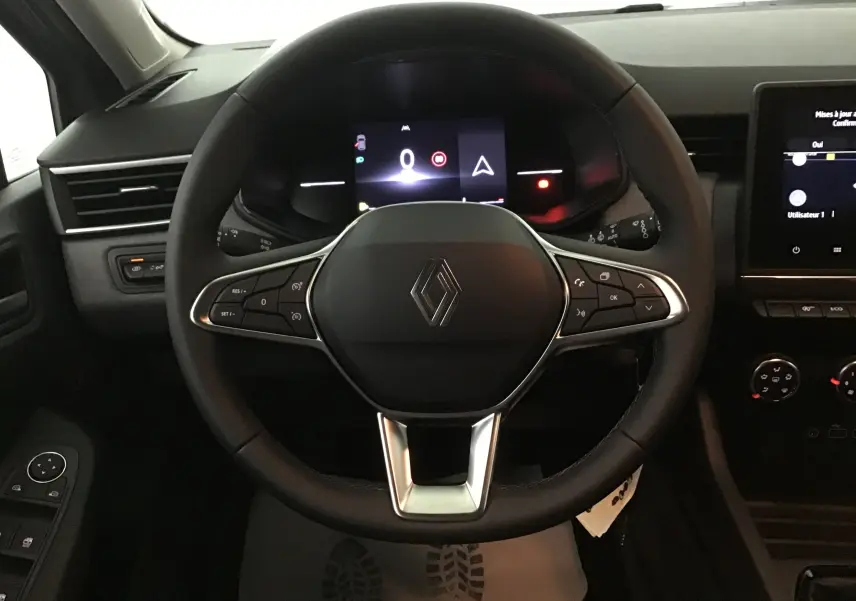 Vue frontale du volant noir de la Renault Clio V 1.5 DCI 100 Evolution avec tableau de bord numérique allumé.