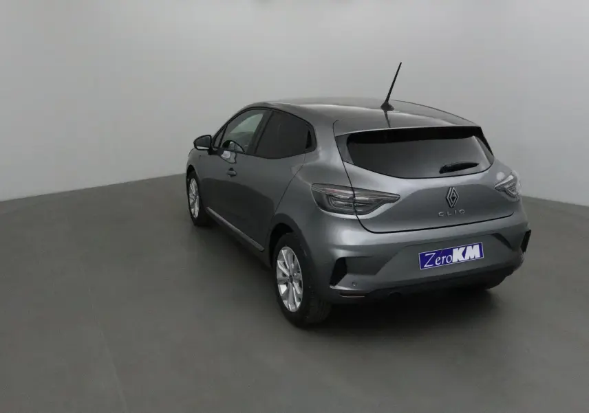 Vue 3/4 arrière droite d'une Renault Clio V gris schiste avec protections latérales chromées dans un studio neutre.