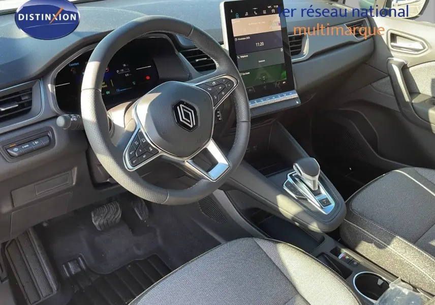 Intérieur du Renault Captur E-Tech 2025, vue côté conducteur sur volant, écran tactile vertical et sellerie tissu gris noir.