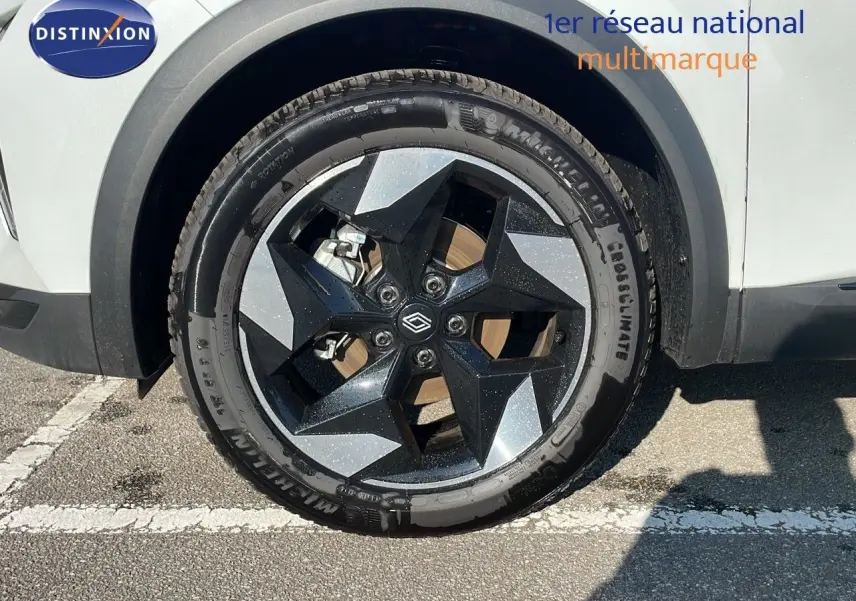 Gros plan sur la roue avant droite du Renault Captur blanc nacré avec jante noire et grise au design géométrique.