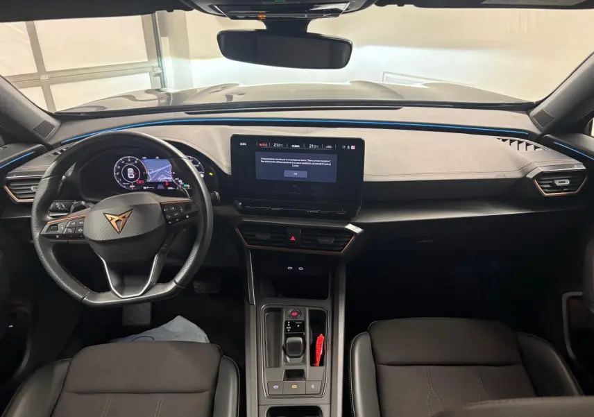 Vue intérieure frontale du tableau de bord du CUPRA Formentor 2024 avec éclairage d'ambiance bleu et écran tactile central.