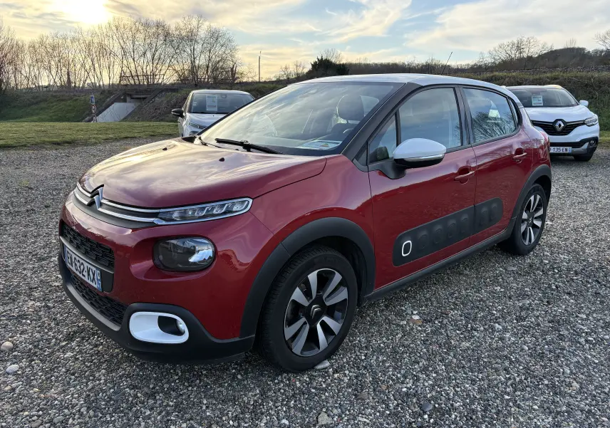 Citroën C3 rouge vue 3/4 avant droit, avec Airbump noir sur les portes et rétroviseurs blancs.