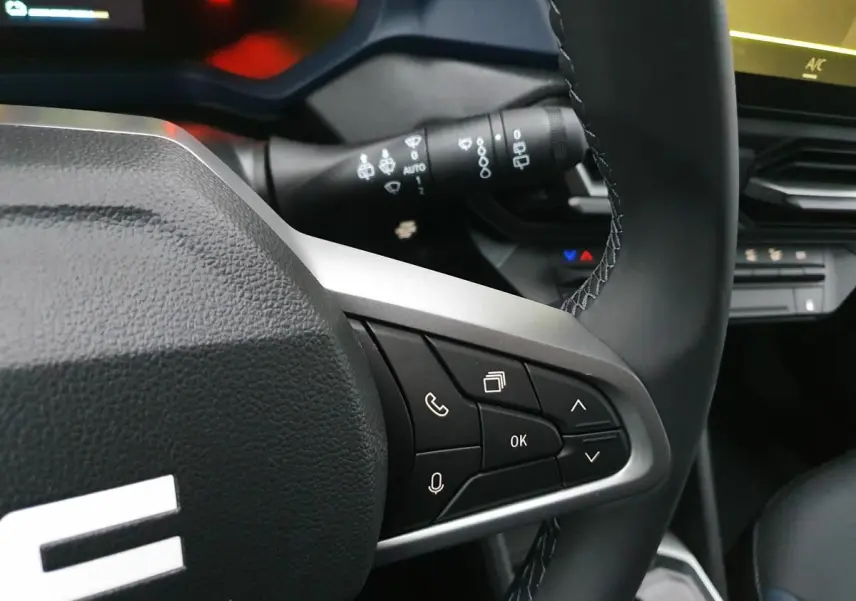 Gros plan sur le volant noir du Dacia Duster 2025 avec commandes multifonctions et tableau de bord partiel.
