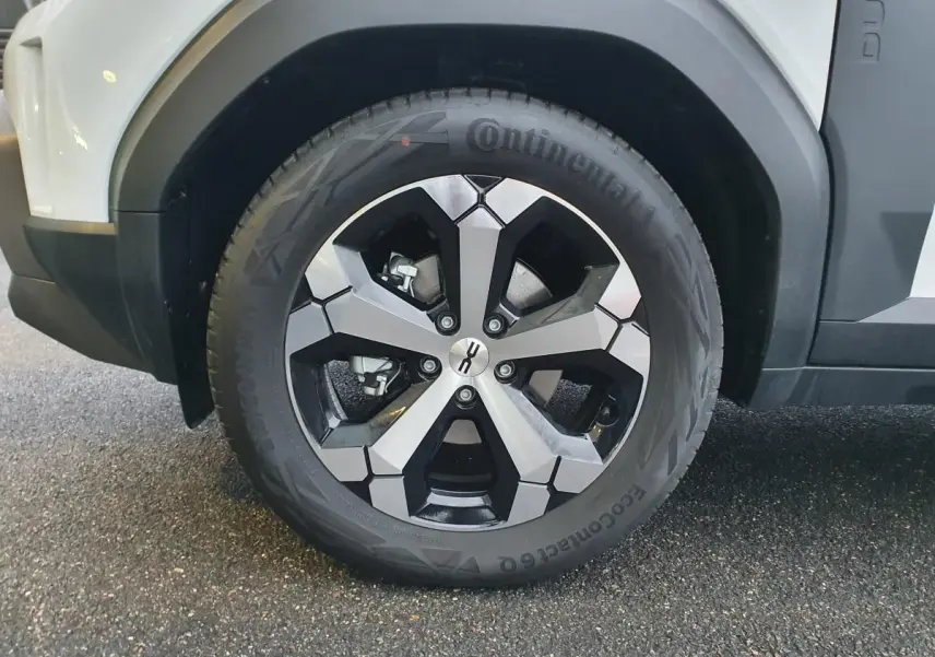 Gros plan sur la roue avant droite du Dacia Duster blanc glacier, jante alliage 18” diamantée Tagasan.