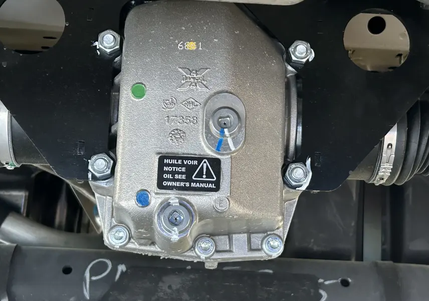 Gros plan sur le boîtier mécanique du pack 4x4 Dangel du Peugeot Partner gris Artense, montrant les fixations et indications d'huile.