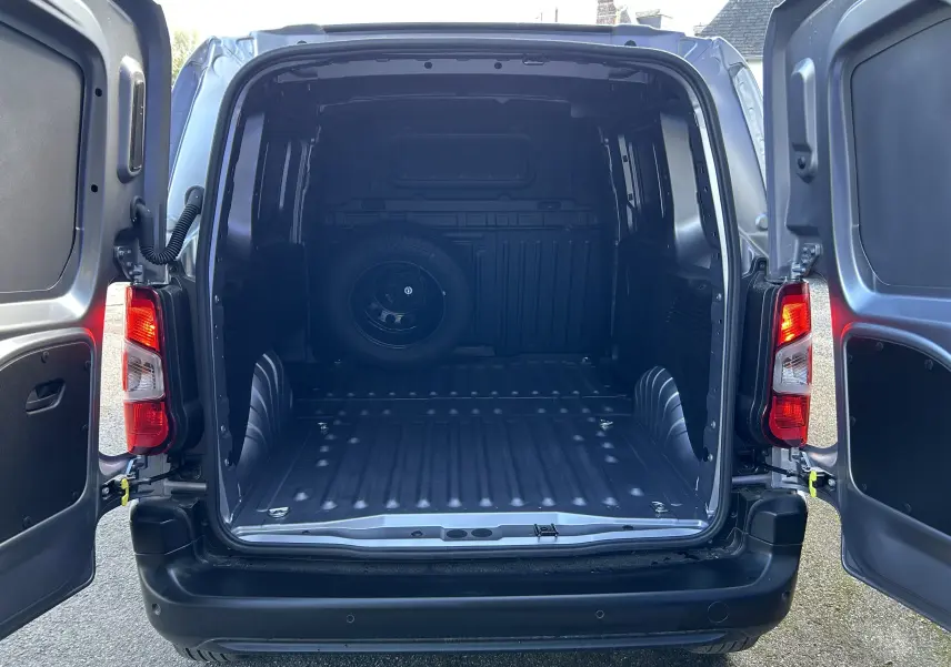 Vue arrière du Peugeot Partner Dangel 4x4 gris Artense avec portes ouvertes montrant l'espace de chargement vide et une roue de secours.