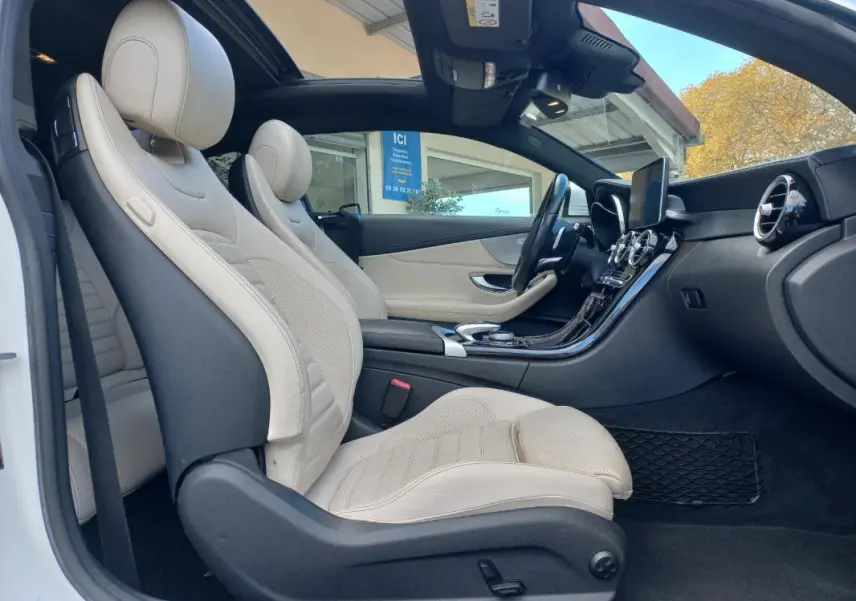 Vue latérale intérieure côté gauche d’une Mercedes Classe C Coupé 2016 avec sièges cuir beige et toit ouvrant électrique.