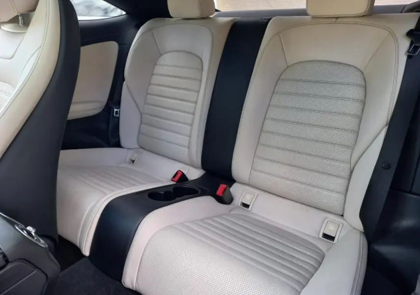 Vue intérieure arrière de la Mercedes Classe C Coupé blanc, sièges en cuir clair avec accoudoir central noir.
