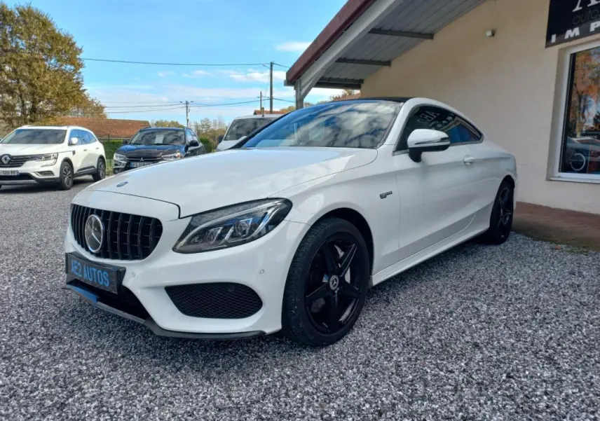 Mercedes Classe C Coupé blanc vue 3/4 avant droit, avec jantes noires et calandre distinctive AMG.