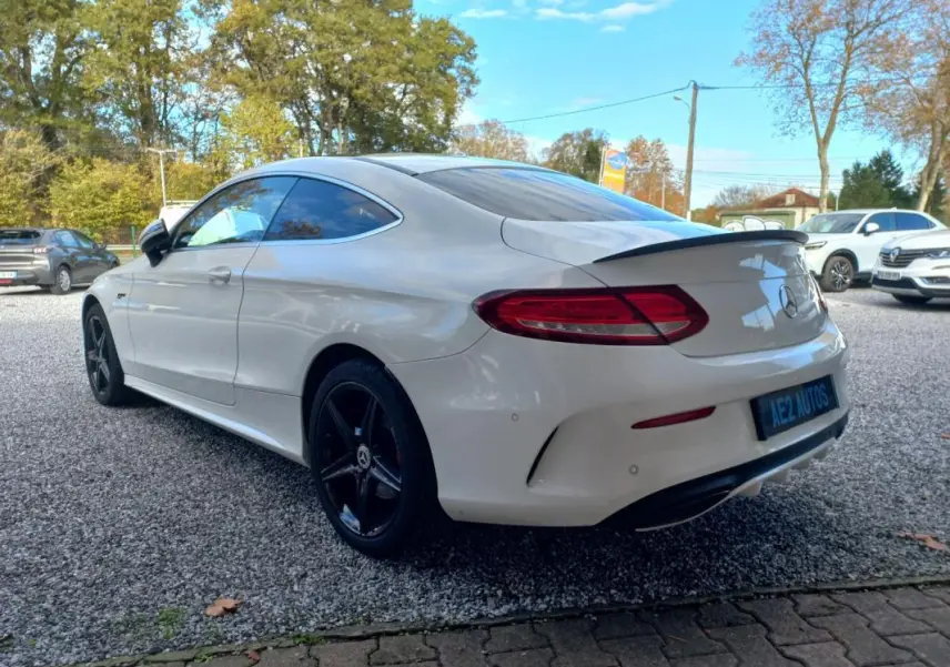 Mercedes Classe C Coupé blanc vue 3/4 arrière droit, jantes noires 18 pouces et toit ouvrant électrique visible.
