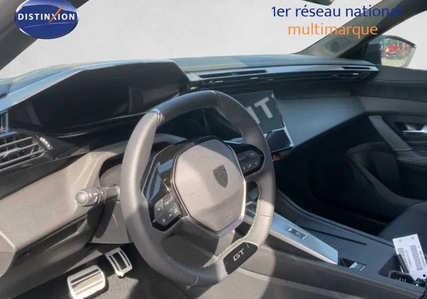 Intérieur de Peugeot 308 Hybrid blanc, vue du poste de conduite avec volant GT et tableau de bord moderne.