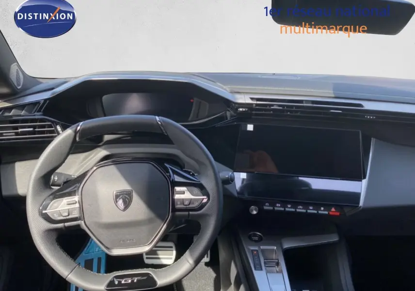 Vue intérieure centrée sur le volant GT et le tableau de bord noir de la Peugeot 308 Hybrid blanche 2026.