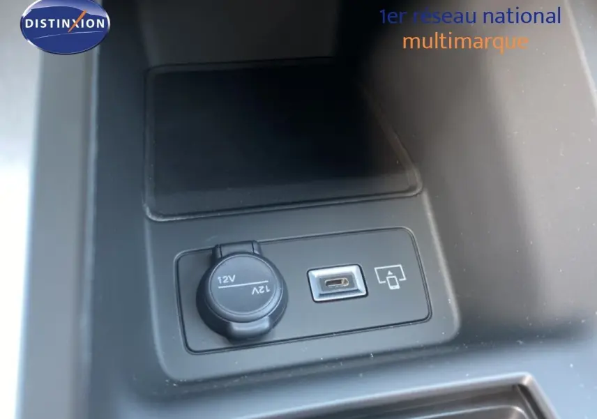 Détail de la console centrale montrant une prise 12V et un port USB dans une Peugeot 308 Hybrid blanche.