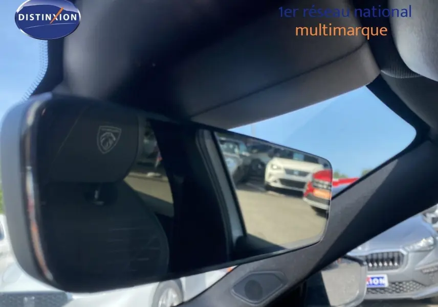 Rétroviseur intérieur de Peugeot 308 Hybrid blanc Okenite, avec reflet du parking et siège au logo visible.
