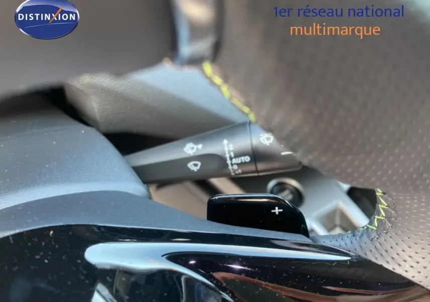 Gros plan sur la palette de changement de vitesse au volant perforé avec surpiqûres jaunes du Peugeot 308 Hybrid blanc.