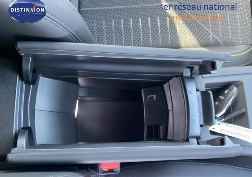 Vue plongeante sur le rangement central ouvert de la Peugeot 308 Hybrid 145ch GT, intérieur noir avec surpiqûres vertes.