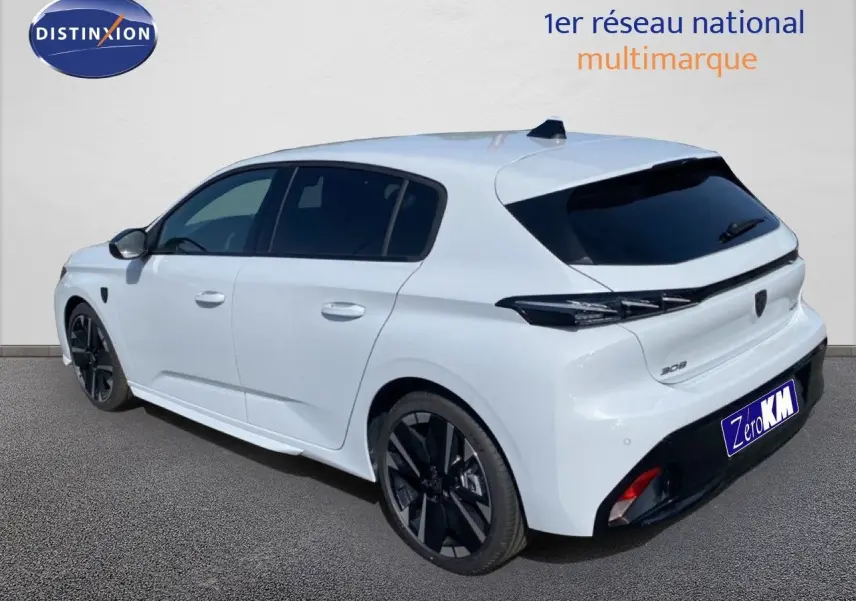 Vue 3/4 arrière droite d'une Peugeot 308 Hybrid 145ch GT blanche Okenite avec jantes noires et vitres teintées.