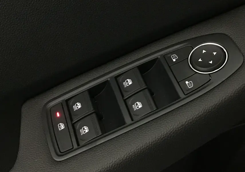 Gros plan sur les commandes de lève-vitres et réglage des rétroviseurs côté conducteur d'une Renault Clio V gris schiste.