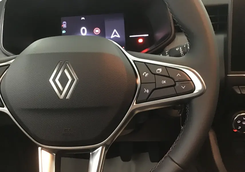 Gros plan sur le volant multifonction de la Renault Clio V 1.5 DCI 100 Evolution, avec commandes et logo central visible.