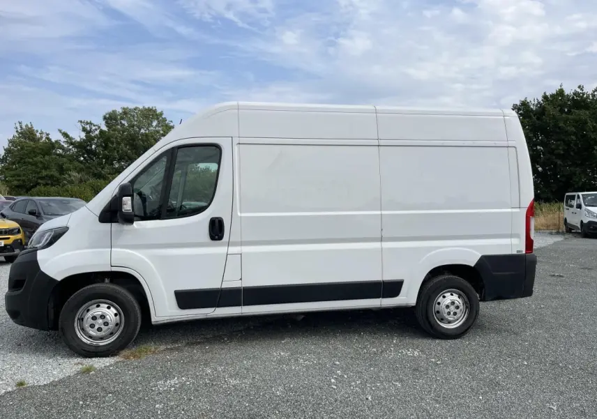 Vue de profil côté gauche d'un utilitaire Peugeot Boxer Fourgon blanc avec porte latérale coulissante et jantes acier.