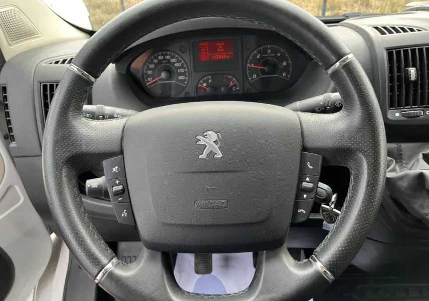 Volant en cuir noir avec logo Peugeot, tableau de bord et compteur digital du Boxer Fourgon 2023 vus de face.