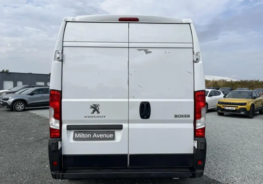 Vue arrière d'un utilitaire Peugeot Boxer blanc avec portes tôlées et feux rouges verticaux.