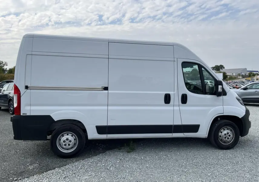 Profil droit d’un utilitaire blanc Peugeot Boxer Fourgon 2023 avec porte latérale coulissante tôlée et jantes acier.