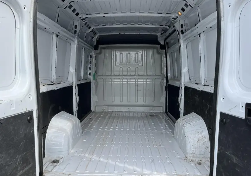 Intérieur vide du fourgon Peugeot Boxer blanc, vue de l'arrière vers l'avant avec cloison tôlée et panneaux latéraux noirs.