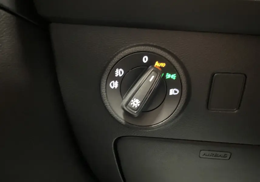 Commande des phares en mode automatique sur tableau de bord noir du SEAT Ateca Rouge Velvet 2024 côté gauche.