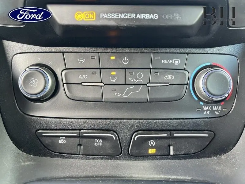 Vue rapprochée du tableau de bord du Ford Transit Connect blanc glacier, montrant les commandes de climatisation et d'airbag passager.