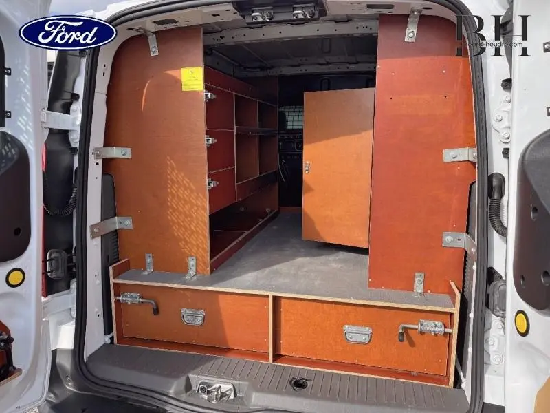 Vue arrière ouverte du Ford Transit Connect blanc glacier, montrant l'aménagement boisé de la zone de chargement avec étagères et tiroirs.