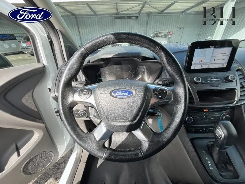 Vue intérieure centrée sur le volant multifonction et la console centrale du Ford Transit Connect blanc glacier de 2019.