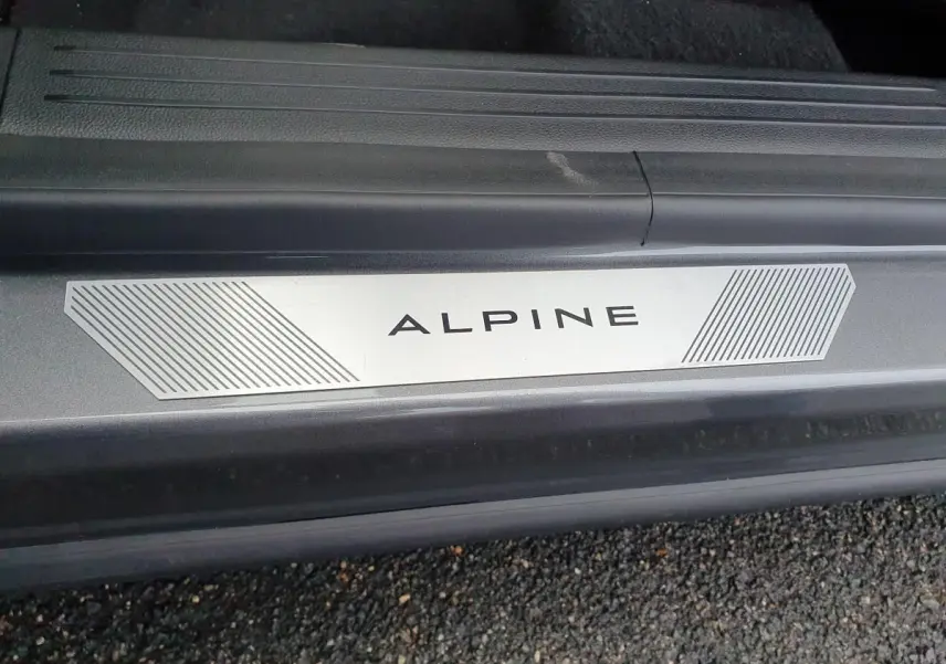 Gros plan sur la plaque de seuil de porte ALPINE du Renault Austral gris schiste avec toit noir visible en arrière-plan.