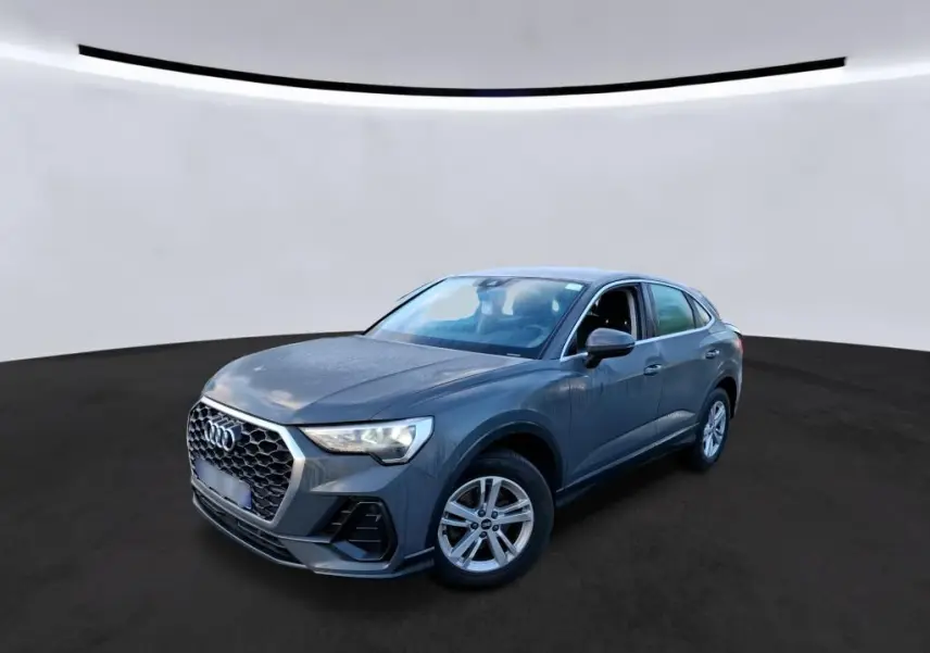 Audi Q3 Sportback gris en vue 3/4 avant droit, avec calandre hexagonale et jantes 17 pouces cinq branches doubles.