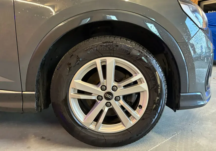 Gros plan sur la roue avant droite gris métallisé d’un Audi Q3 Sportback avec jante aluminium 5 branches doubles.